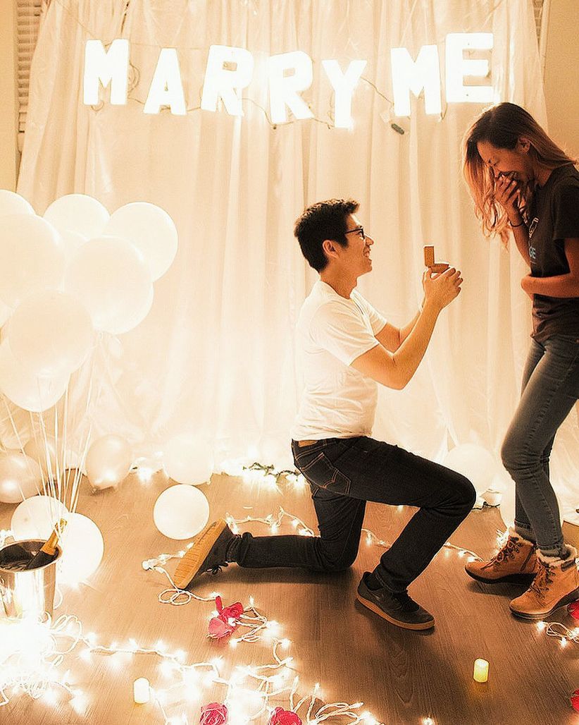 proposal at home with string lights and champagne