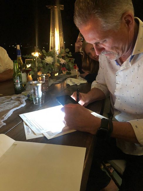 Our amazing friend, host and officiant signing the marriage certificate by cell phone light. 
