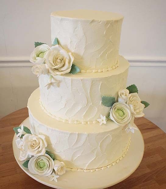 white round wedding cake with roses and greenery