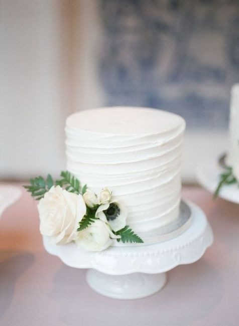 small wedding cake on stand with flowers