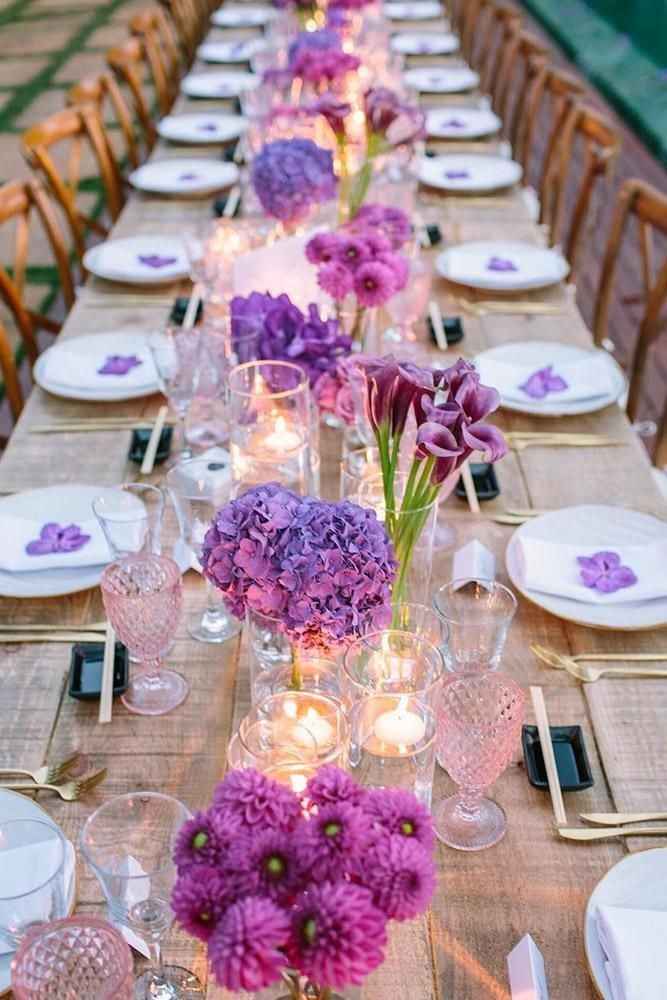 wedding centrepiece with little vases and purple flowers long table