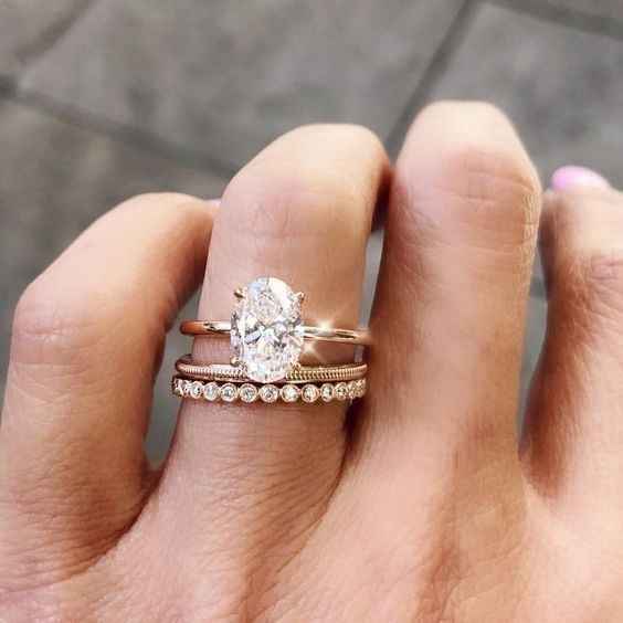 oval engagement ring with rose told band and twisted wedding band