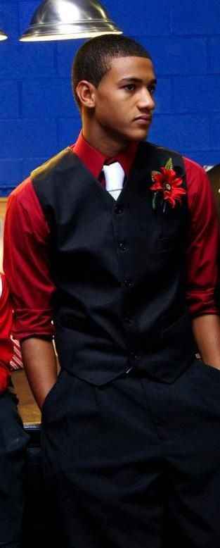 dark red shirt, black vest, white tie and flower
