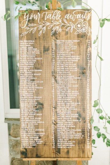 wooden guest list sign with greenery and script writing 