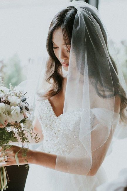 bride with vneck dress holding a bouquet wearing a veil
