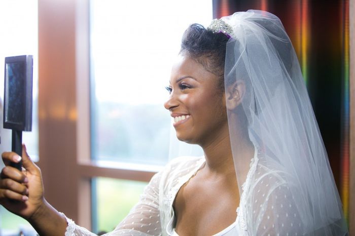bride wearing a veil looking into mirror