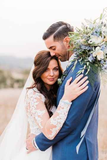 couple holding each other with blue bouquet in field by Brittany Taylor Photography in CA