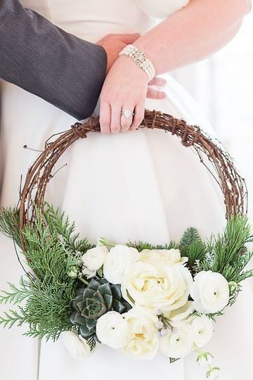 Bride holding branch hoop bouquet with white flowers and succulents