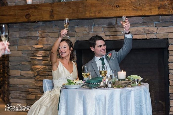 Couple toasts with champagne glasses at sweetheart table