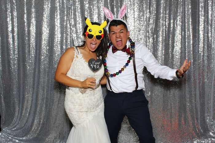 Newlywed couple in photo booth with fun accessories 