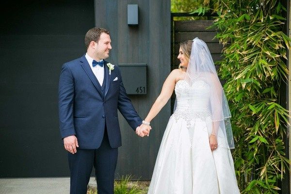 Groom in navy tux and bride in white gown and veil holding hands