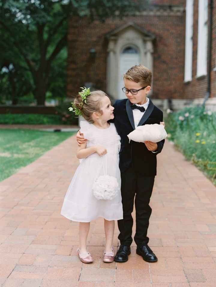 flower girl ring bearer hugging in a white dress and bag and a bowtie and white pillow