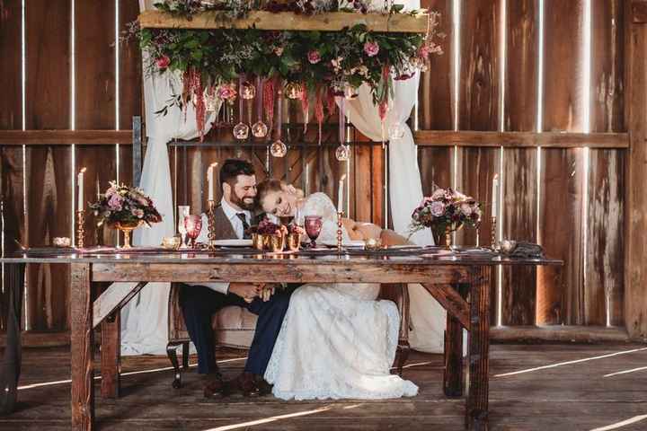 Rustic barn sweetheart table with candles and floral background