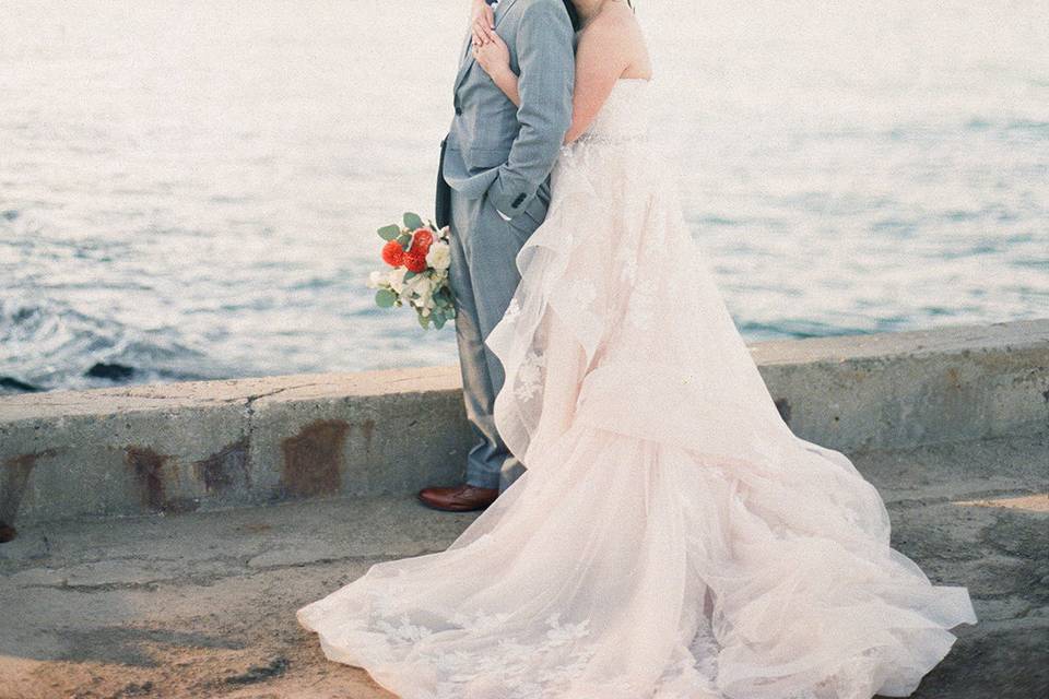 Bride embraces her groom by the sea