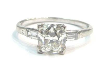 Antique cushion cut diamond engagement ring with baguette cut diamond accents, in an engraved Art Deco platinum ring.