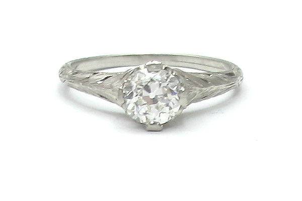 Vintage, Art Nouveau-inspired solitaire engagement ring from the early 20th century. An old European cut diamond is set in platinum with botanical engraving down the sides.