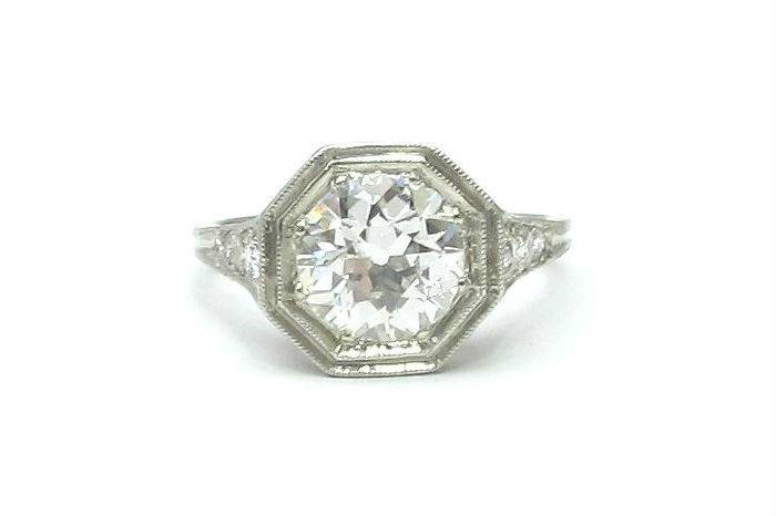 Geometric Art Deco platinum engagement ring with a old European cut diamond center and single cut diamond accents in the shoulders of the ring. Bold design with a milligrained, octagonal top.
