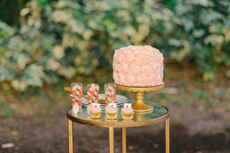 Gluten free and vegan rose frosting covered three tier cake , mini cupcakes and individual parfait cake shots.