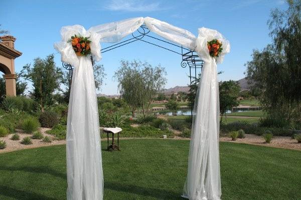 Arch decorated in white organza bows with floral center to match wedding colors.