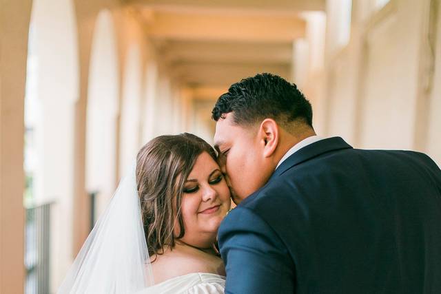 Bride embraces her groom as she gets kissed | Makeup: Hamaholic Studio. Photo: Michele Shore Photography. Hair: Stephanie's Beauty Artistry