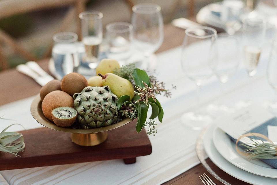 centerpiece including antique brass filled with local produce & greenery on a custom handmade walnut serving tray.  Air plants held custom place cards at every seat.