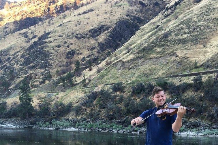 Chris playing the violin by the river