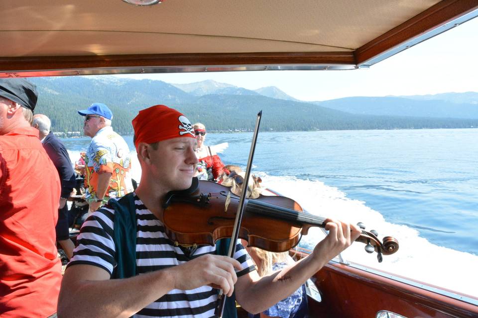 Chris playing the violin on a boat