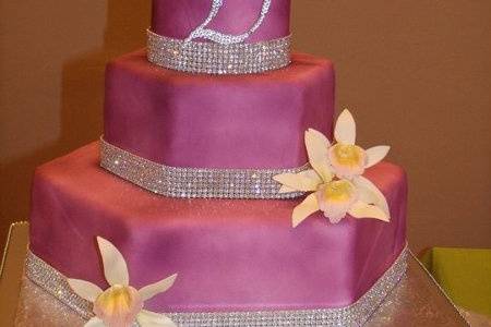 3-tier fondant covered hexagon wedding cake with Swarovski crystal banding at the base of each tier, Swarovski crystal initial.  Handmade gumpaste Phaius orchids complete the design.