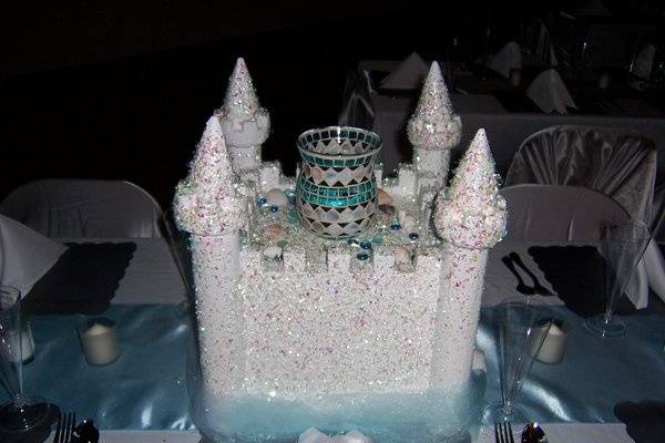 Elegant Sand Castle centerpiece with beach theme hurricane and floating candle. When used for Cinderella theme the hurricane would be changed with a clear glass and a feather boa is added. The tulle around the bottom would be changed to white.