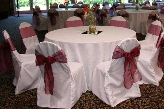 White chair covers with red organza bows.