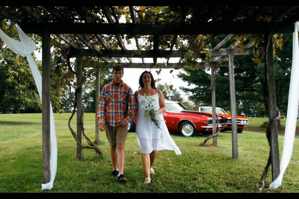 Jen Packer walks through grape trellis with son Noah on her way to the altar