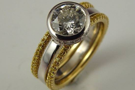 Round brilliant cut diamond in platinum with fancy yellow diamonds in yellow gold.
