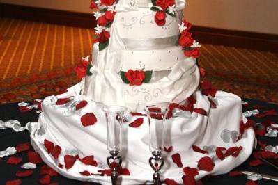 Handpainted Red sugarpaste roses, white stephanotis with silver accents and fondant ribbon.