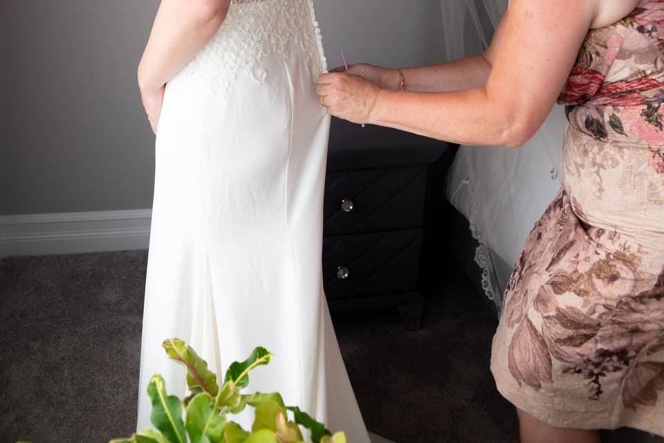 Mom helping bride into dress