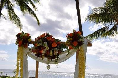 Ceremony archway with chairs facing ocean view and flowers lining the aisleway at Lanikuhonua