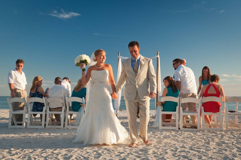 Happy couple walk from their beach wedding ceremony on Sanibel Island