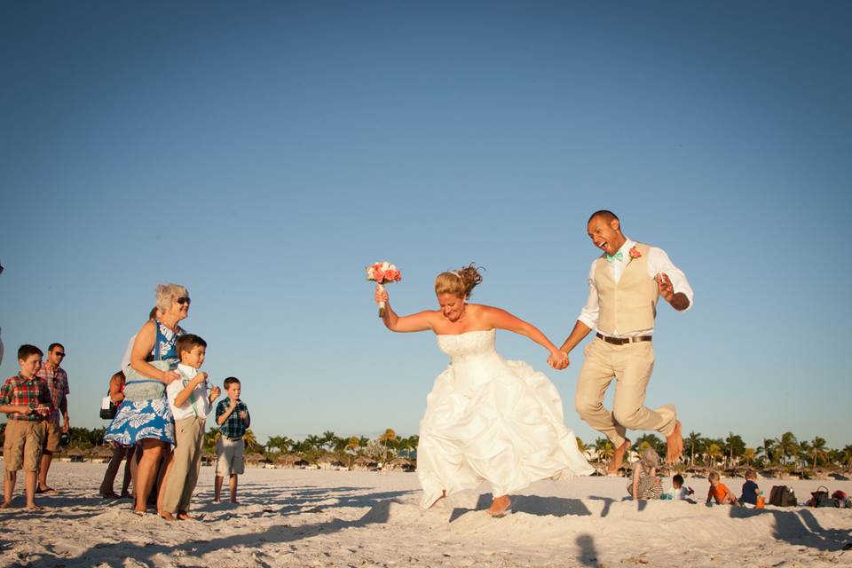 Happy bride and groom jump from their ceremony onto the beach on Marco Island