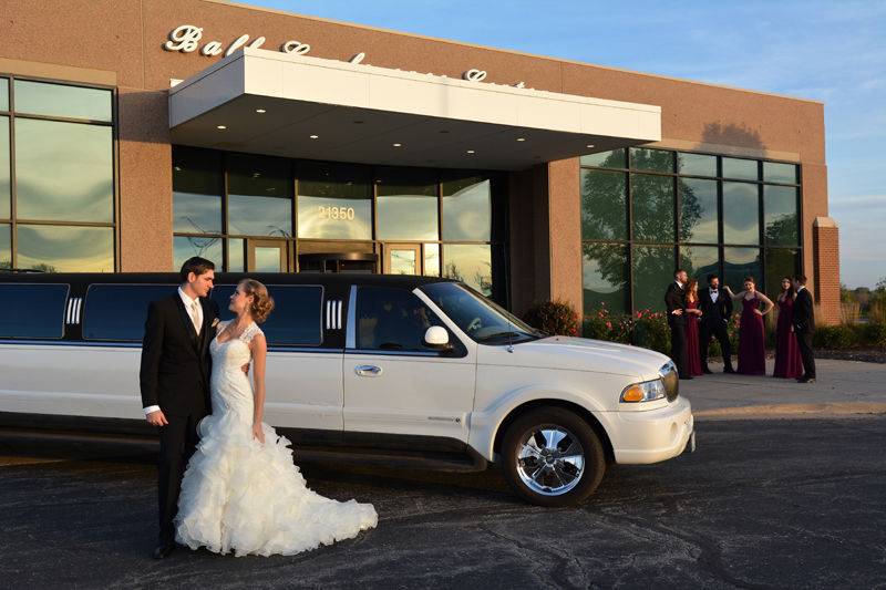 Newlyweds by their limousine