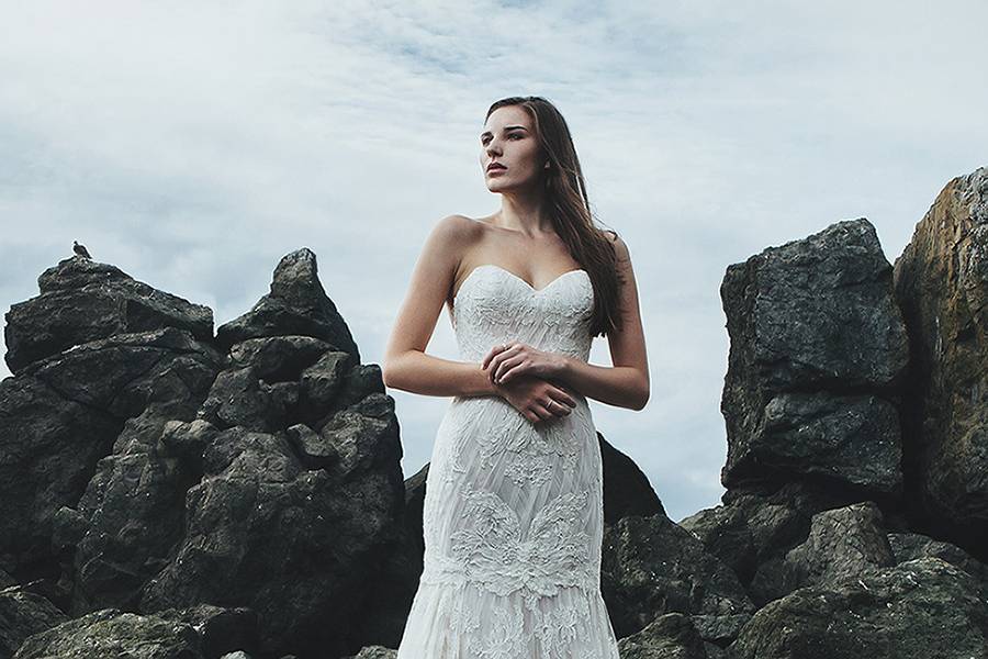 BriarStrapless ivory silk crepe gown with a minimal mermaid silhouette. A Swarovski crystal belt on a thin Mokuba ribbon defines the waist with Italian embroidery on tulle throughout the bodice and the sheer skirt overlay.