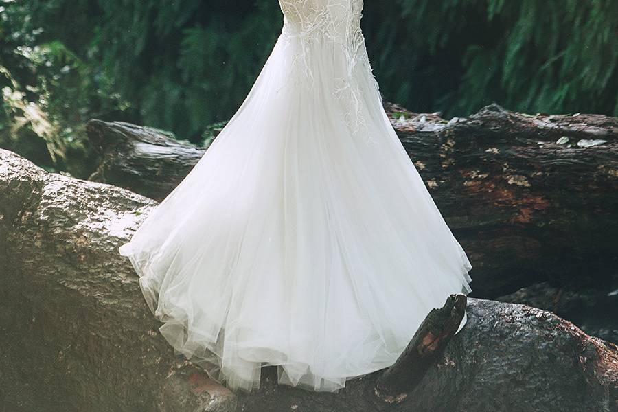 BorealStrapless sweetheart gown with a dramatic asymmetric mermaid silhouette. Layers of airy silk tulle are ruched on the bodice, complimented by an ivory tree embroidery. A low back is supported by a sheer organza inner corset.