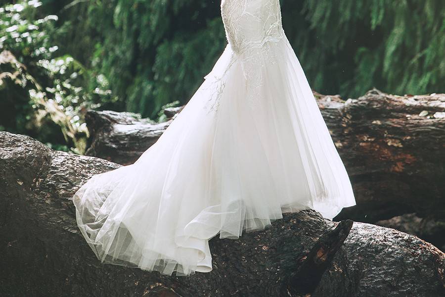 BasiliaSlim mermaid gown made from silk crepe back satin. A re-embroidered French Chantilly lace overlay with a corded lace scallop hem compliment the sheer beaded lace panels. Delicate strands of silver beads create a shimmering cowl effect over the open back.