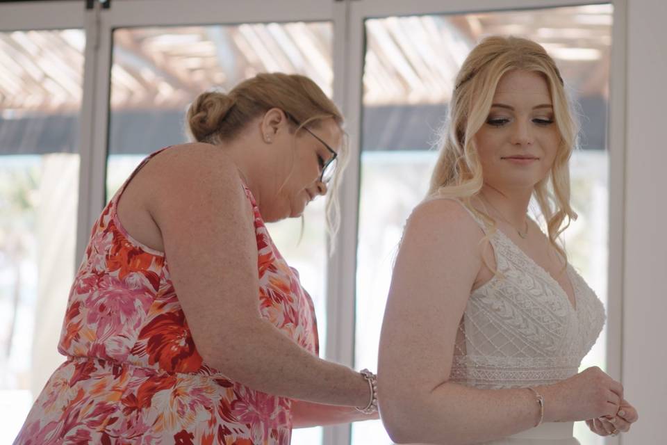 Mother helping bride with dres
