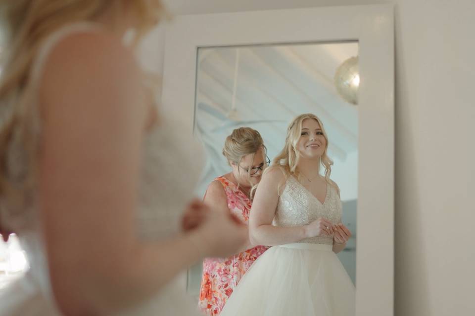 Mother helping bride with dres