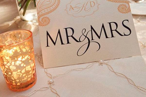 Tented 'Mr. & Mrs' table sign for sweetheart table. Monogram and paisley design. Gold and black inks printed on champagne shimmer paper.