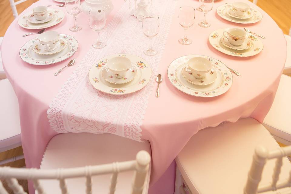 Tea party table set-up with light pink tablecloth, White lace table runner, and candelabra centerpiece.