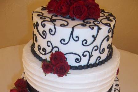 Fresh red roses compliment the white banding and black scroll work of this cake