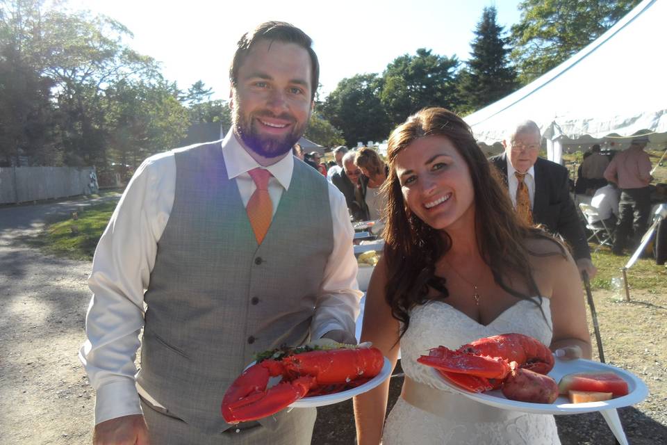 Newlyweds with lobster dinner at their tented reception.
