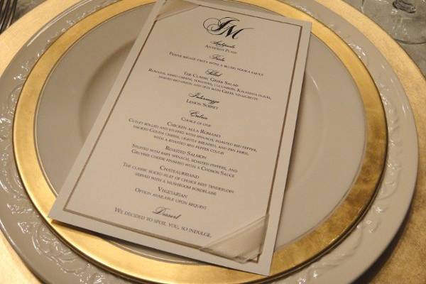 Custom gold and black wedding menu printed on linen paper and accented with ribbon corners.