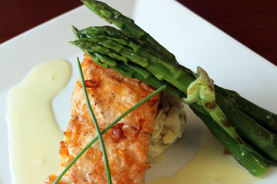 Pan seared salmon filet with lemon Buerre Blanc sauce, dill puréed potato and grilled asparagus bundle with a chive garnish.