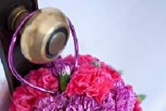 Flower girl pomander of hot pink and purple mini carnations and fuchsia handle.